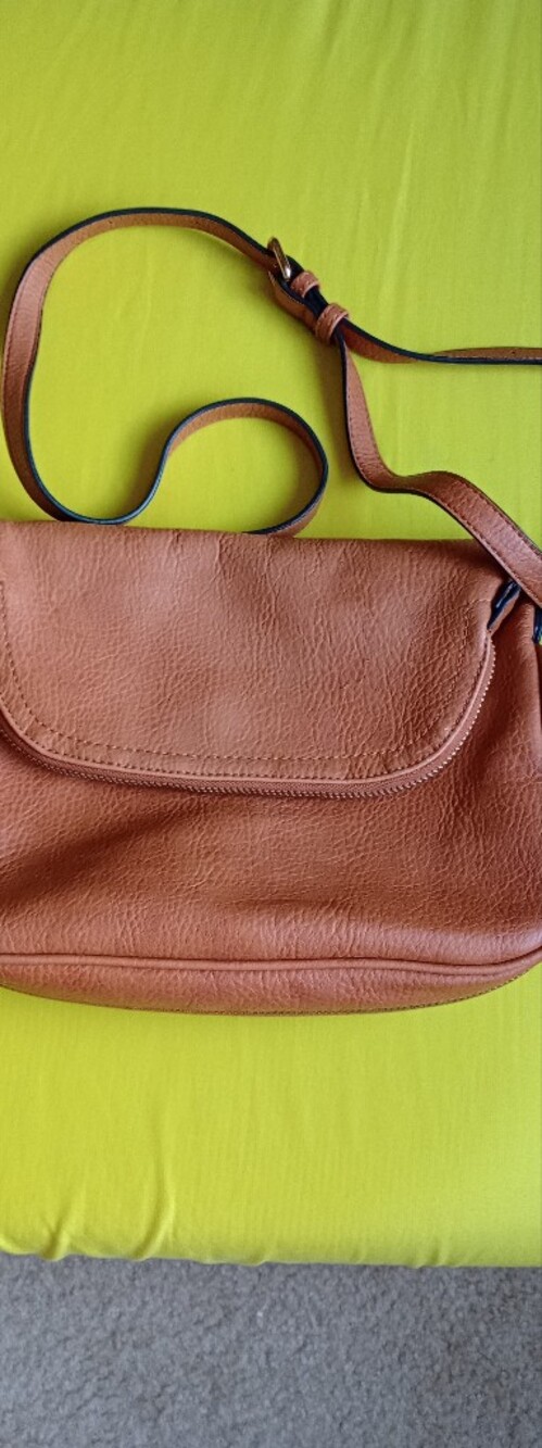 tan Fossil leather crossbody travel bag featuring a zipper on the front flap.